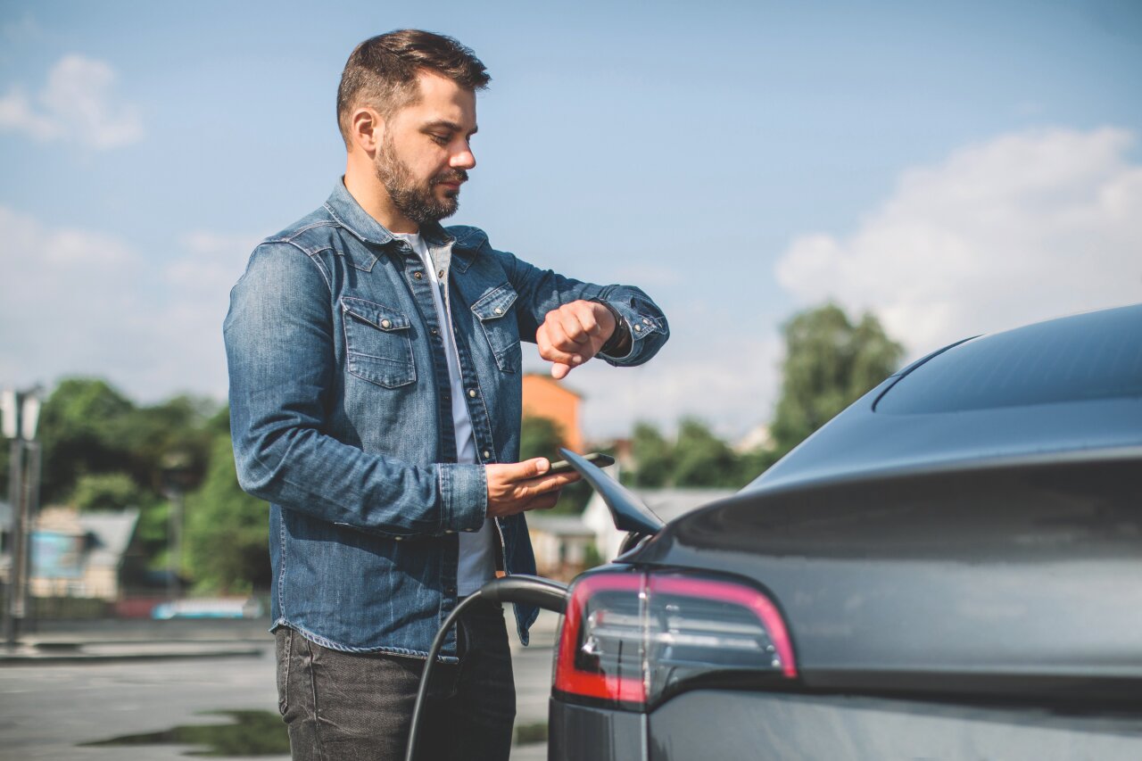 Mann lädt sein E-Auto